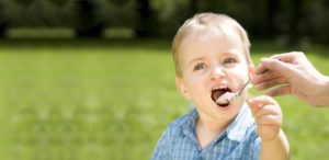 Junge auf Wiese isst Joghurt